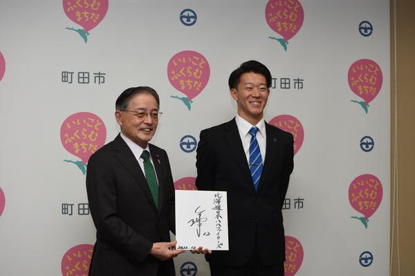 矢澤選手と矢澤選手のサインを手にして笑顔の石阪市長の記念撮影の様子