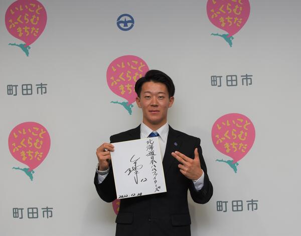 サイン色紙を片手に新庄監督考案のポーズをとる矢澤選手